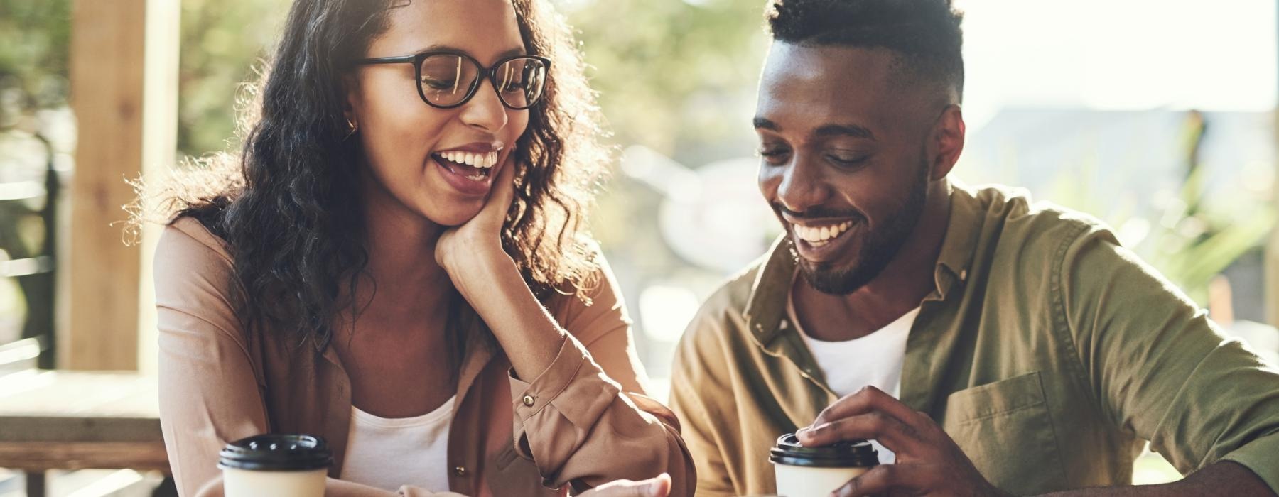 a man and woman sitting at a table with coffee cups